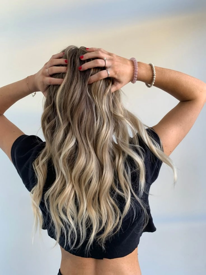 Woman with balayage highlights and beach wave styling for a relaxed coastal look