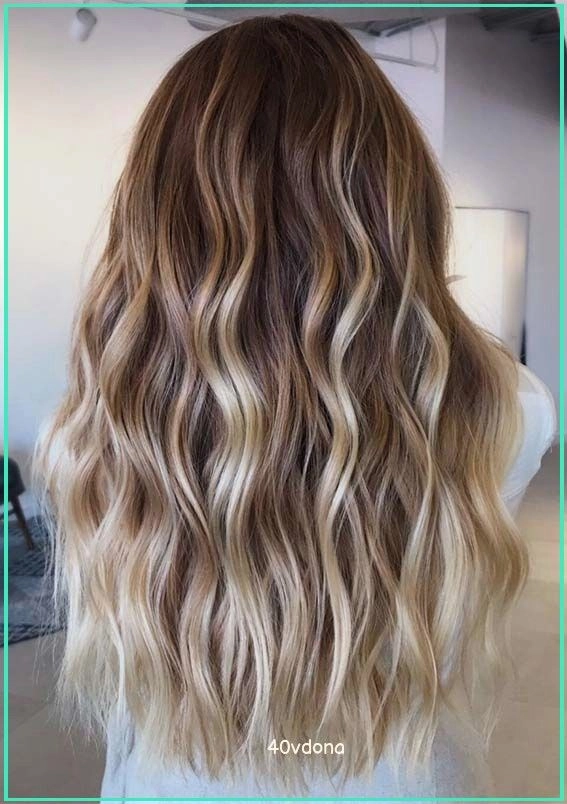 Woman with balayage highlights and soft beach waves against a seaside backdrop