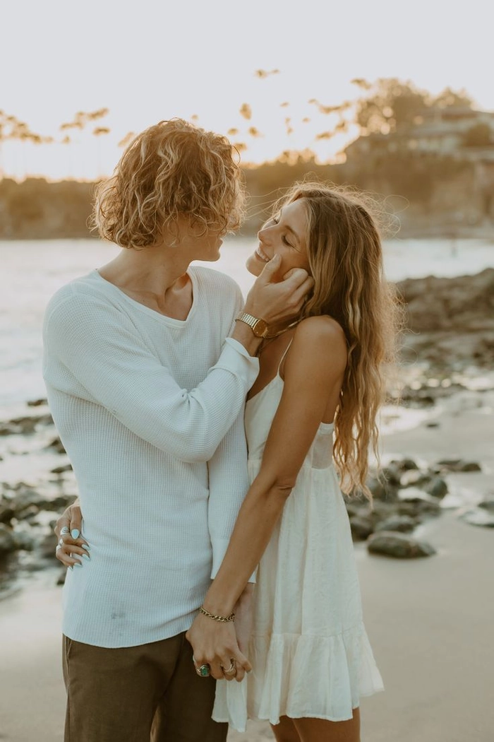 Trendy beach engagement session hairstyles featuring effortless waves and natural accessories Bride with loose beach waves and a floral crown during an engagement session on the sand