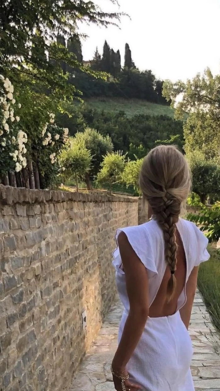 Woman with a messy beach french braid, windswept strands framing her face