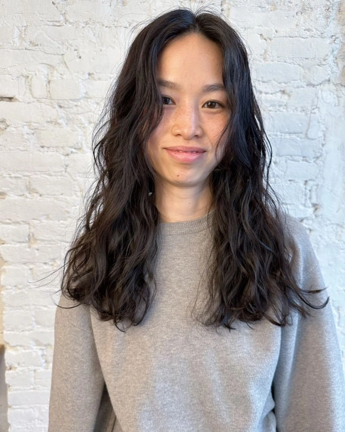 Voluminous beach waves softening a round face at the shore