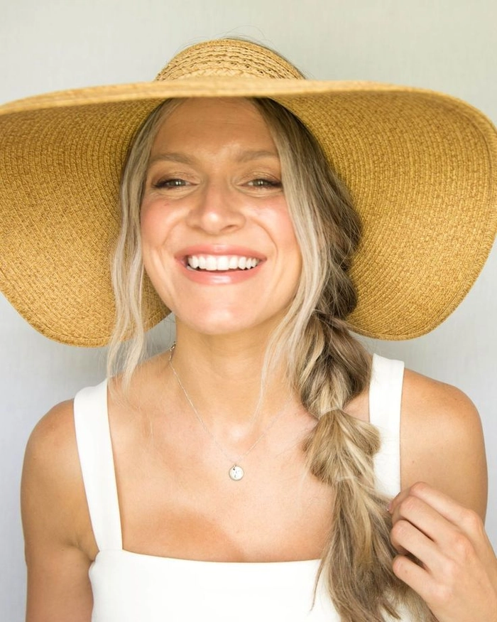 Loose beach waves cascading from under a stylish wide-brimmed hat