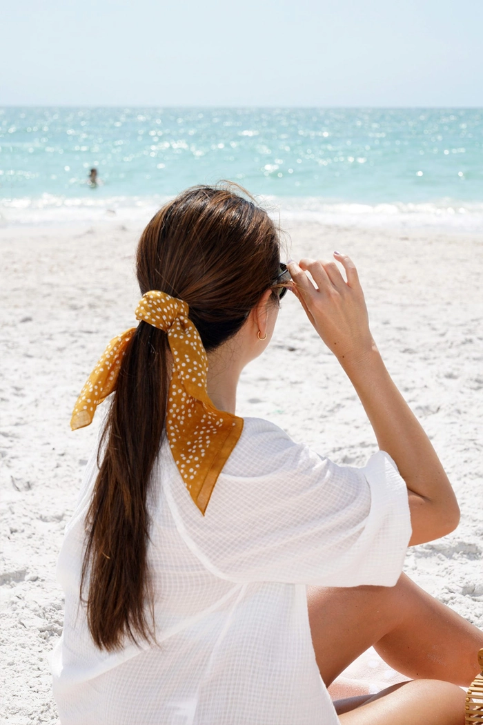 Silk scarf beach hair look for sunny days Beach hairstyle with a silk scarf wrapped around a loose braid
