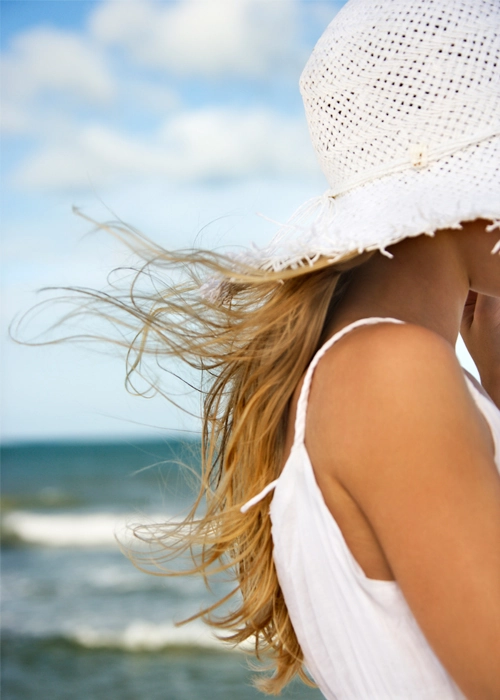 Woman smiling with wind-tousled beach hair that stays smooth and frizz-free in high humidity