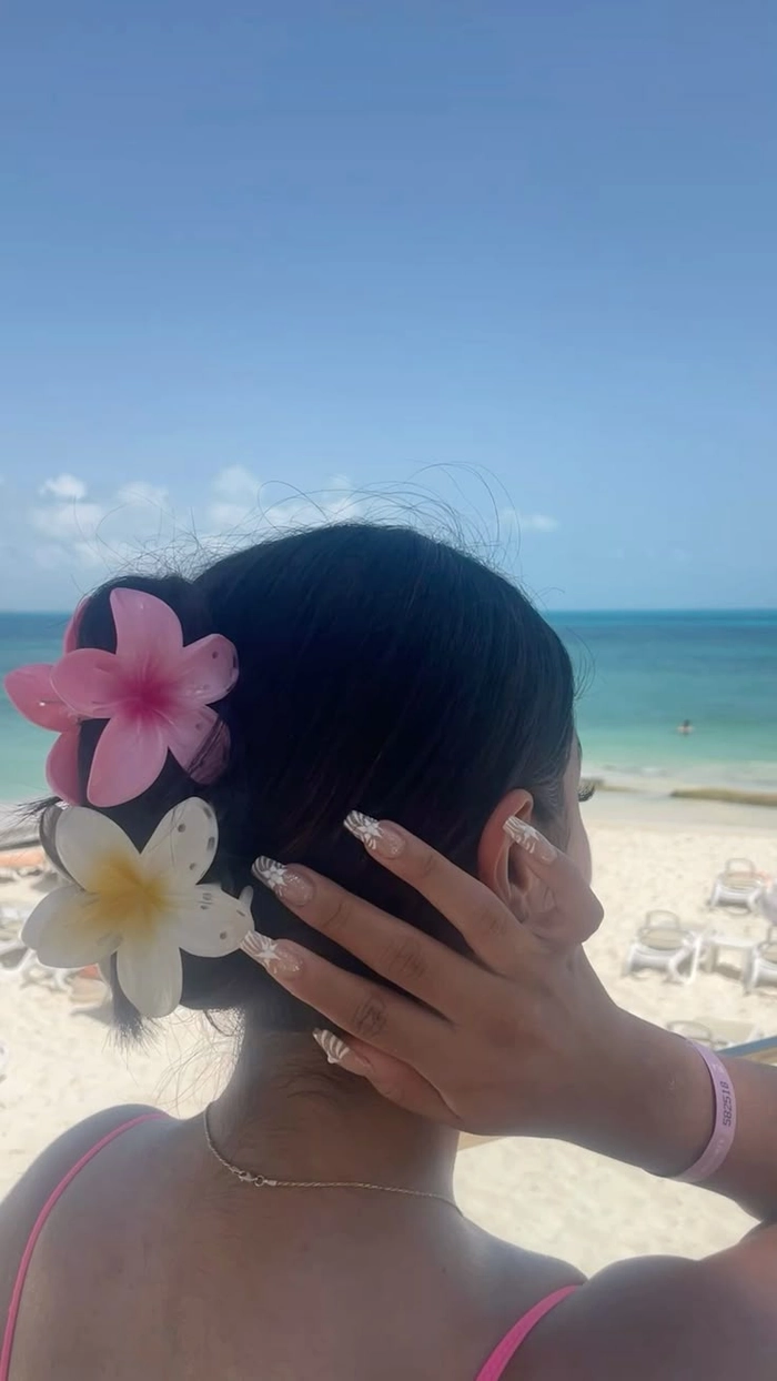 Beach hair adorned with fresh tropical flowers blowing in ocean breeze
