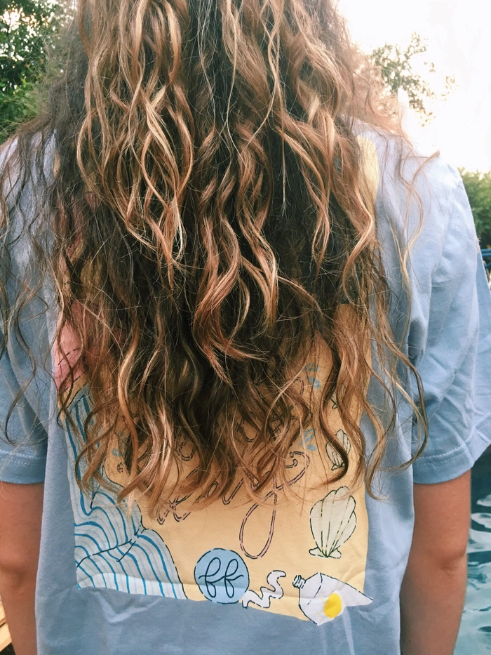 Woman with naturally curly hair styled in a messy beach wave updo with sea salt texture