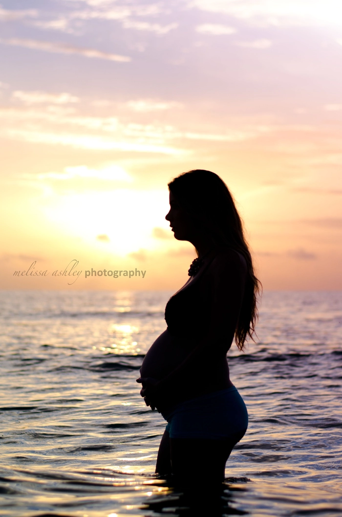 Beach maternity session hair styled with soft waves and natural movement Maternity beach hairstyle flowing in the ocean breeze during a photoshoot