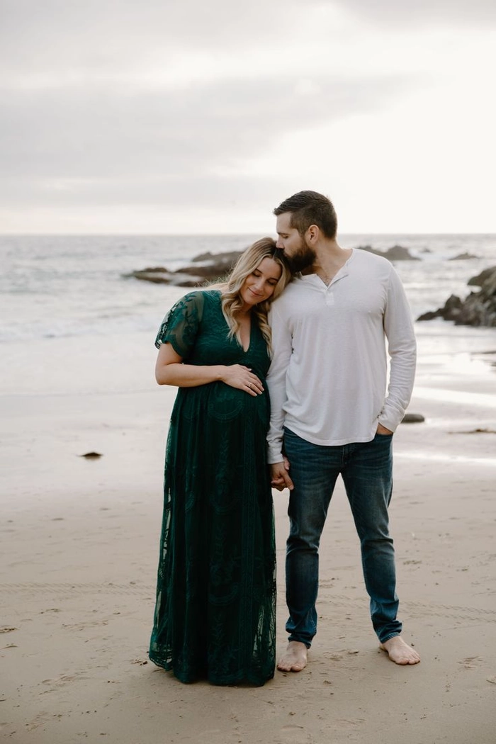 Beach maternity session featuring soft, natural waves for a seaside hairstyle Pregnant woman with beach waves and windswept hair at sunset maternity photoshoot