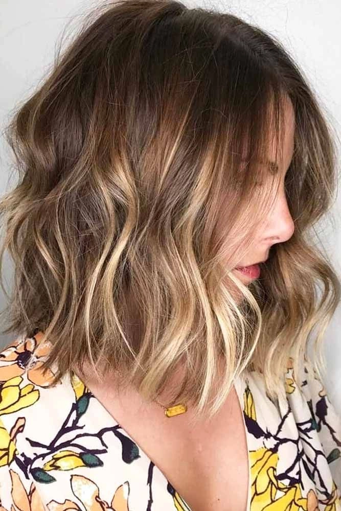 Woman with medium length hair styled in beachy waves, soft tousled texture and natural highlights