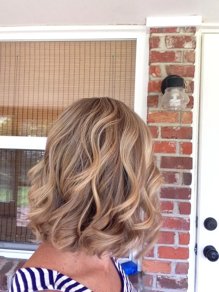 Woman with a bob cut hairstyle at the beach, wind-tousled waves