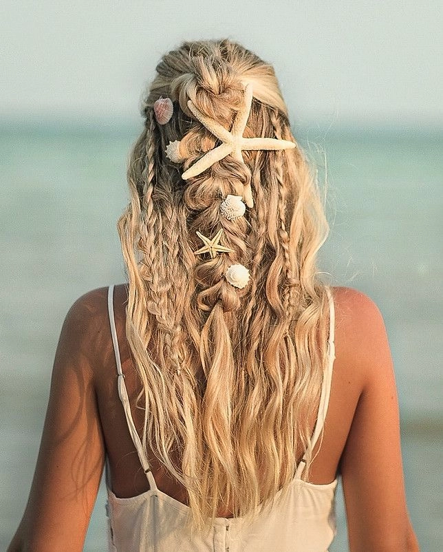 Woman with tousled braided hair and seashell accessories at a sunny beach