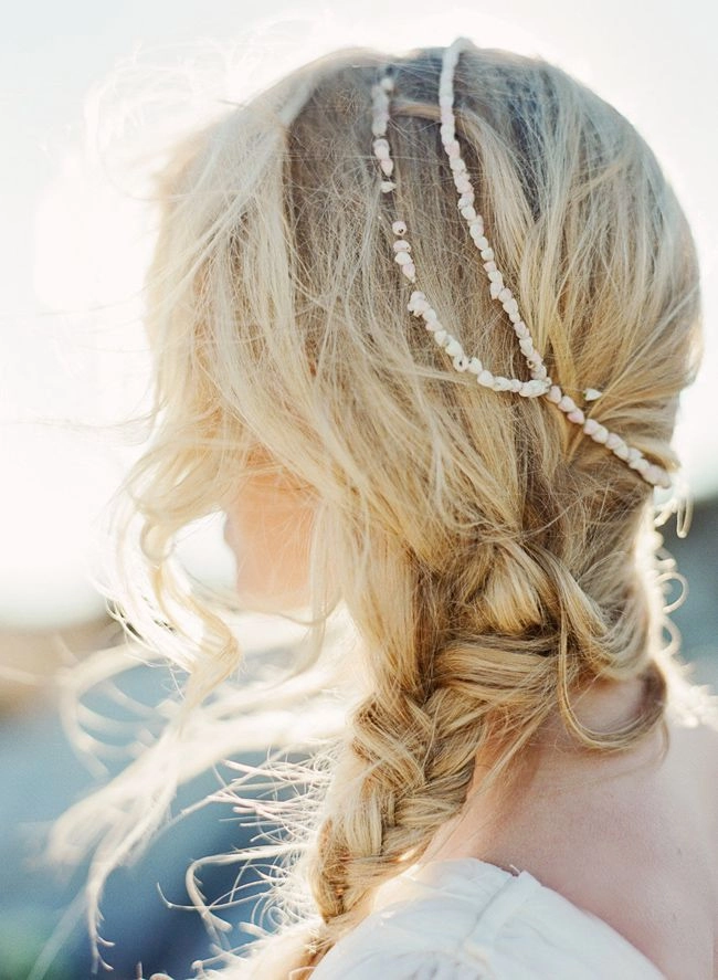 Beach hairstyle for an elopement bride featuring natural texture and ocean-inspired details Coastal elopement hair inspiration with soft, tousled waves and a delicate flower accent