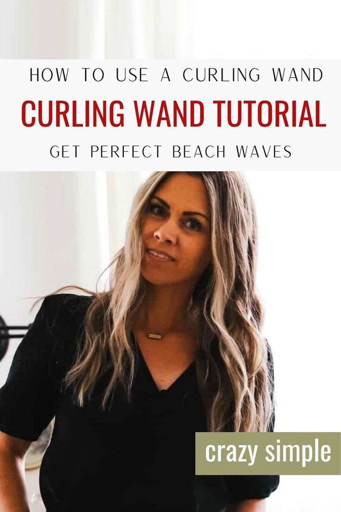 Woman styling beach waves with a curling wand on medium-length hair