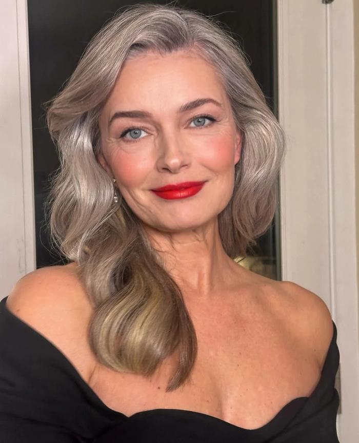 Elegant gray-haired woman with soft waves and a silver clip enjoying a calm beach sunset