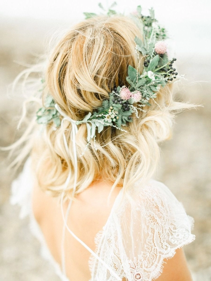 A woman with a floral crown and loose beach waves smiles at the shore