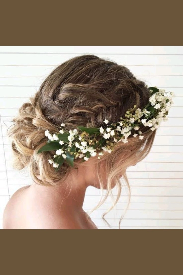 Woman with a floral crown and loose beach waves smiles while styling her hair by the ocean