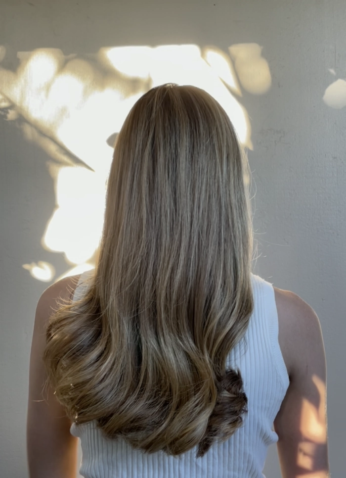 Beach hairstyles hack for frizzy hair in humidity Woman with frizzy hair using humidity hacks at the beach
