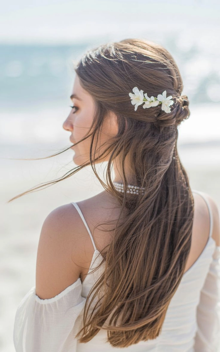 Half up half down beach hair style with loose waves and breezy texture Woman with tousled half up half down beach hairstyle, soft waves and natural volume