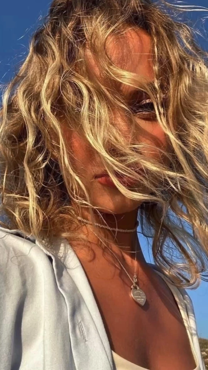 Woman with bleached beach hair applying leave-in conditioner after swimming