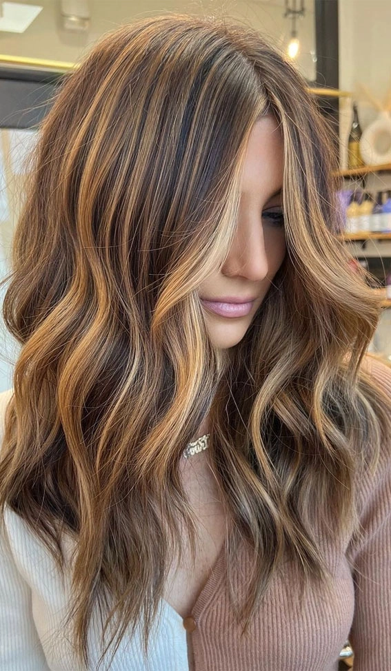 Woman with sun-kissed blonde highlights in loose beach waves at the seaside