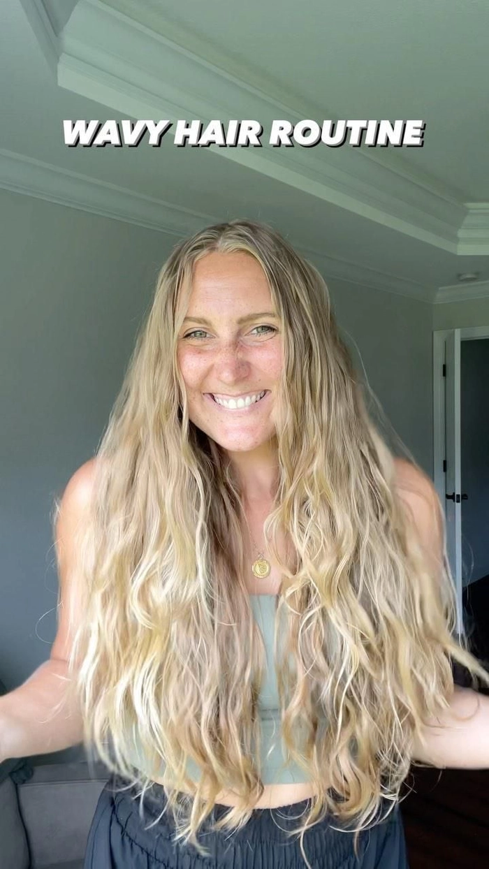 Beach Wave Routine: Enhancing Natural Texture Woman with wavy hair applying leave-in conditioner at sunny beach