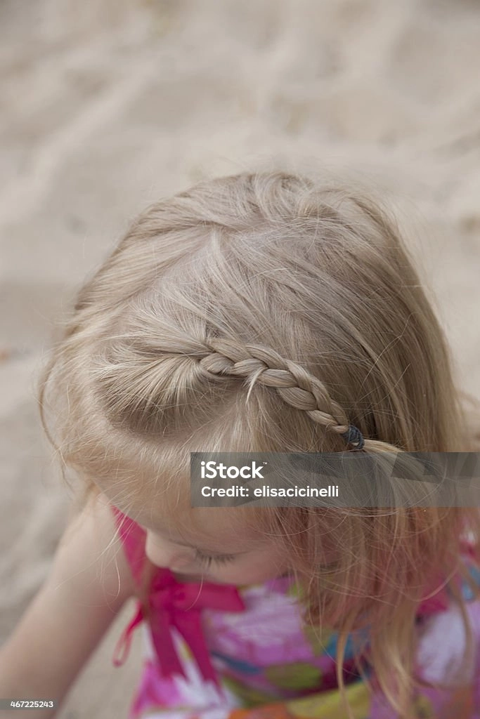 Beach braids hairstyle for a little girl at the seaside Little girl with beach braids smiling on the sandy shore