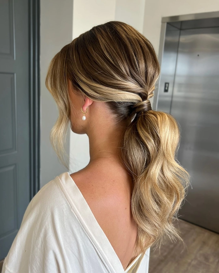 A low beach ponytail with tousled waves and face-framing strands