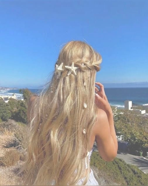 Mermaid core beach hair with soft waves and golden highlights on the sand