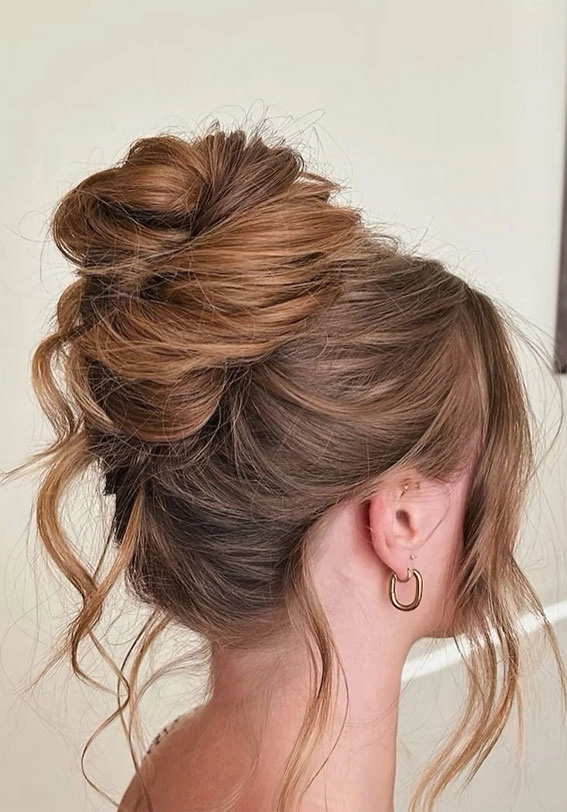 Messy beach bun hairstyle with soft, undone texture and face-framing strands