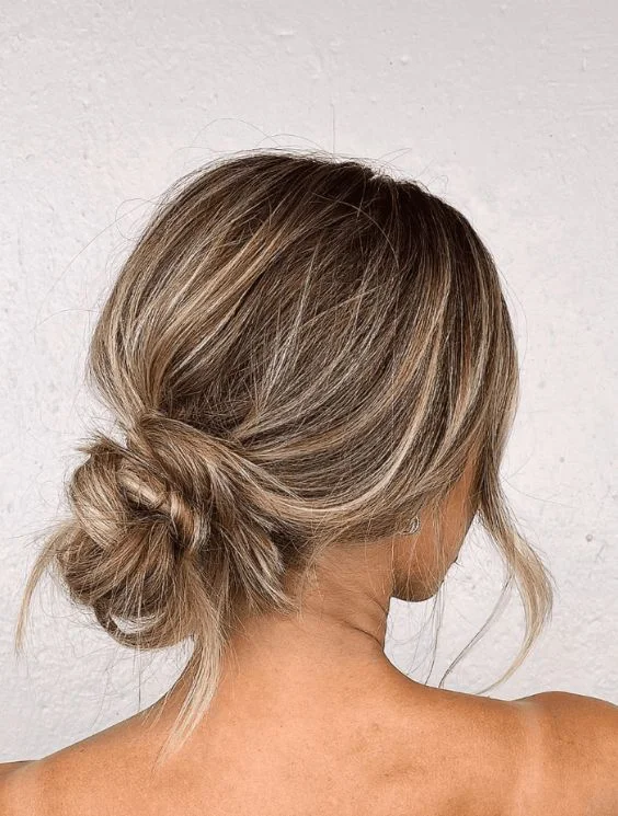 A carefree messy beach bun hairstyle with loose strands
