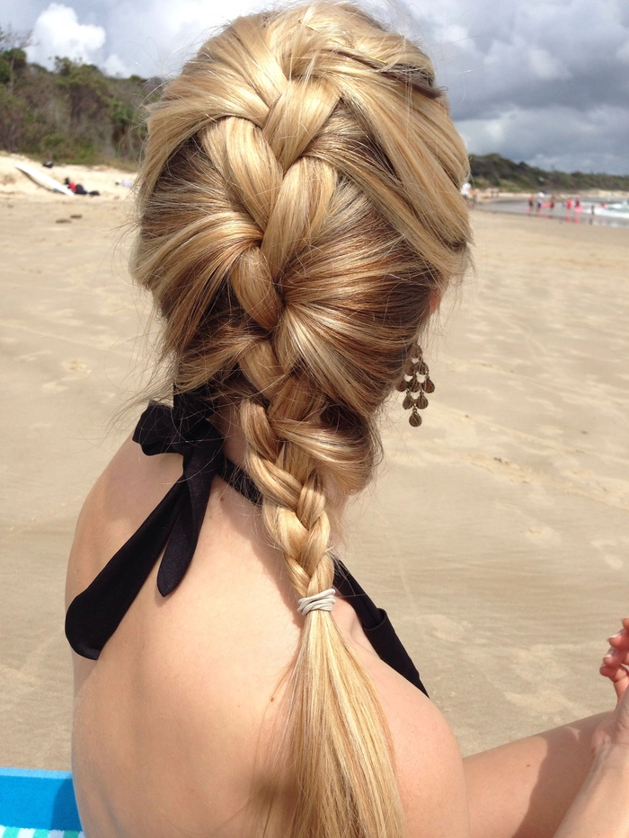 A woman with a long ombré beach braid styled loosely on a sandy shore