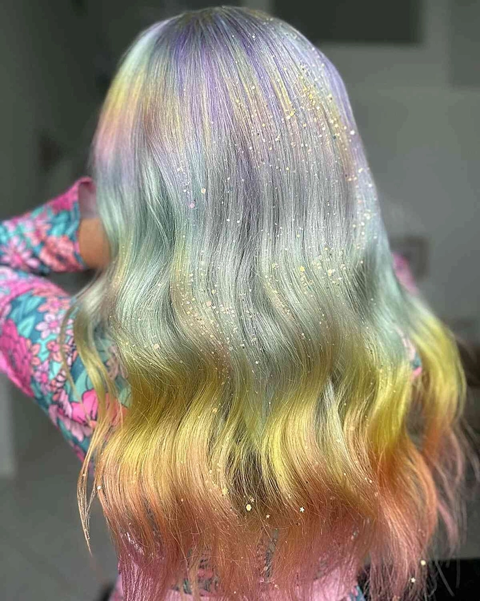 A woman with pastel lavender hair styled in tousled beach waves while standing on the sand