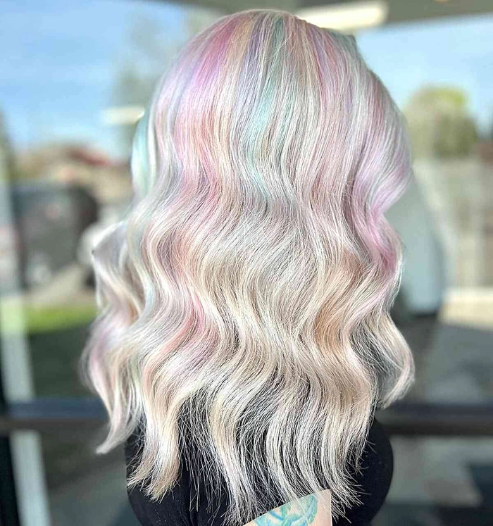 Woman with pastel pink hair styled in beach waves, enjoying the seaside breeze