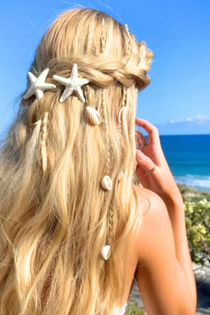 Woman with pastel blue-green hair tousled in beachy waves against a sandy shoreline