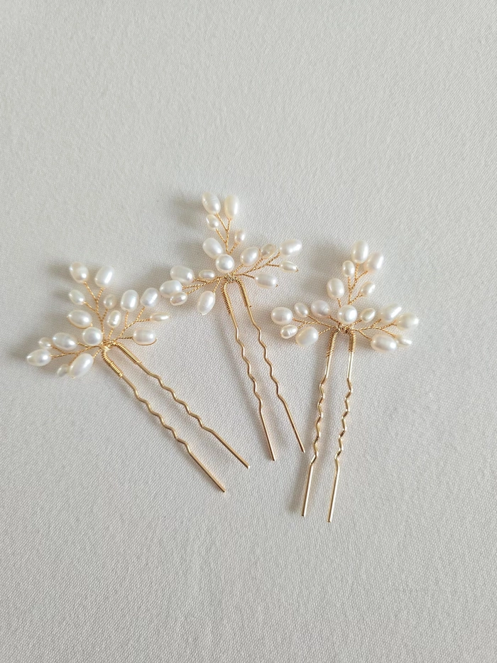 Pearl hair pins accenting a beach updo with soft waves and ocean backdrop