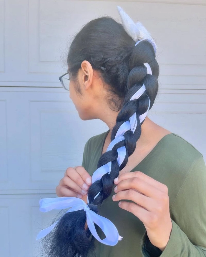 Woman with ribbon tied beach braids smiling at ocean
