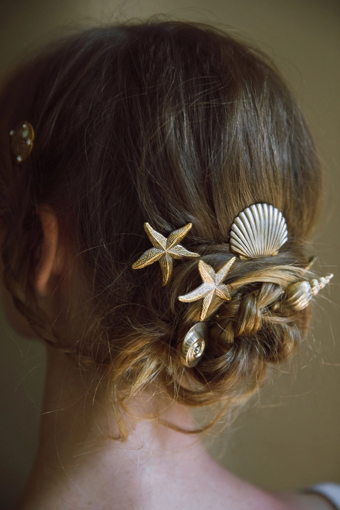 Delicate seashell hairpins and clips adorning a loose beach wedding updo with soft waves