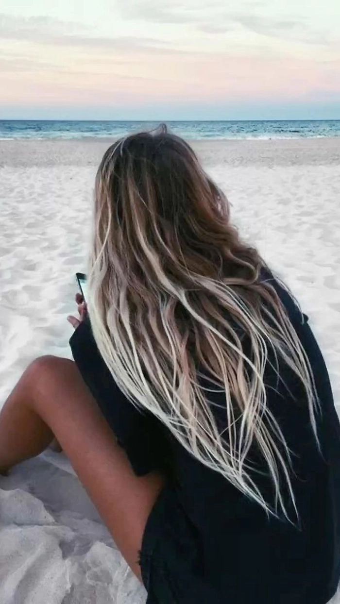 Surfer girl with tousled beach waves and sun-kissed highlights, blowing in ocean breeze