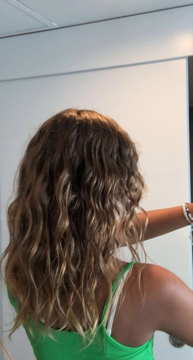 Surfer girl with tousled beach waves and sun-kissed highlights showcasing effortless hairstyle for seaside vibes