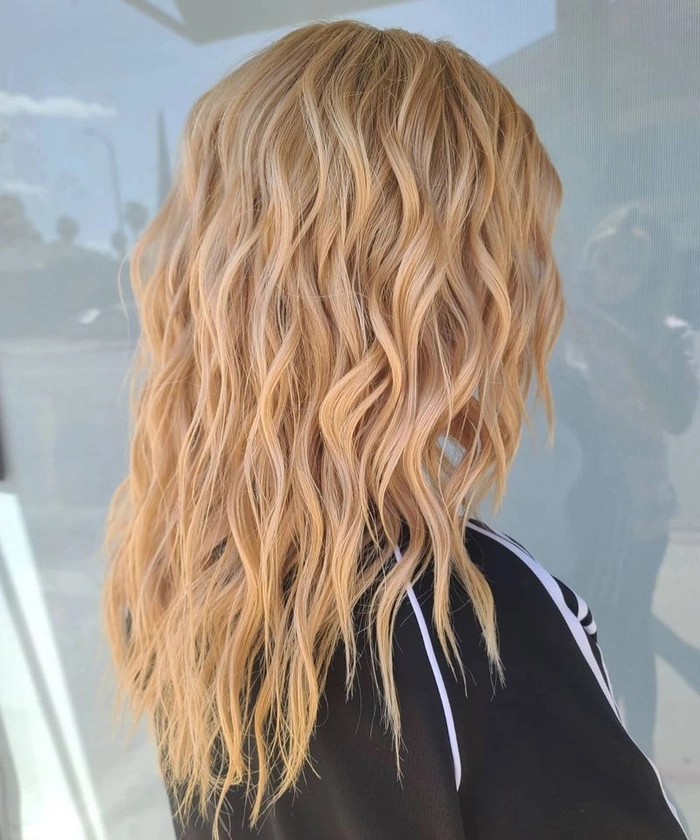 Woman with thin hair styled into messy beach waves using texturizing tricks for volume