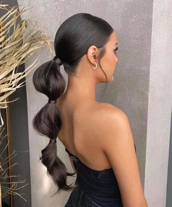 Casual bubble braid ponytail hairstyle on long hair with loose strands