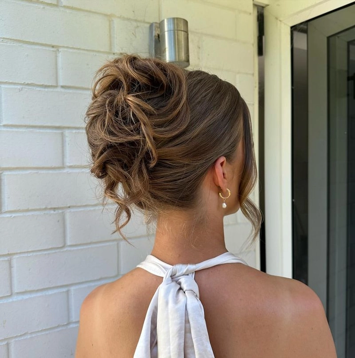 Casual messy bun style on long hair with loose strands for a relaxed look