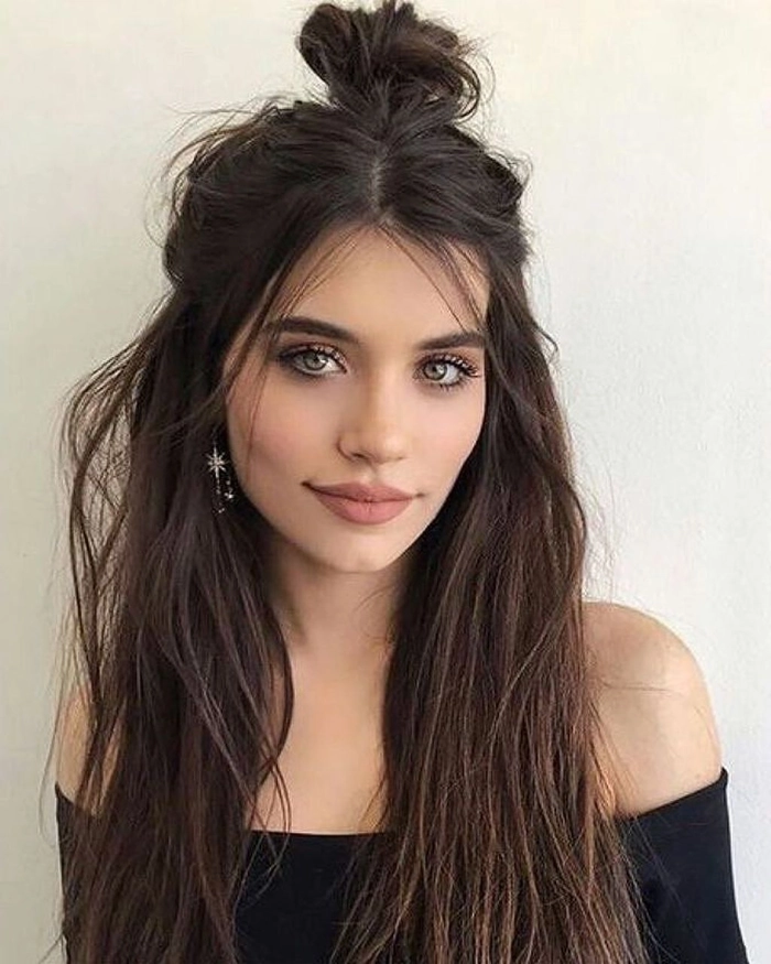 Casual messy bun style on long hair with loose strands for a relaxed look