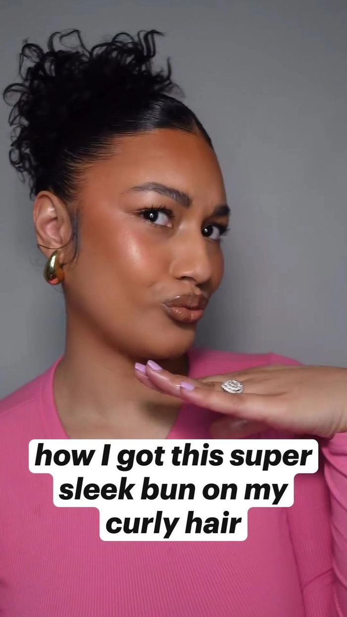 Woman with curly hair styled in an easy, sleek slicked back bun for a casual look.