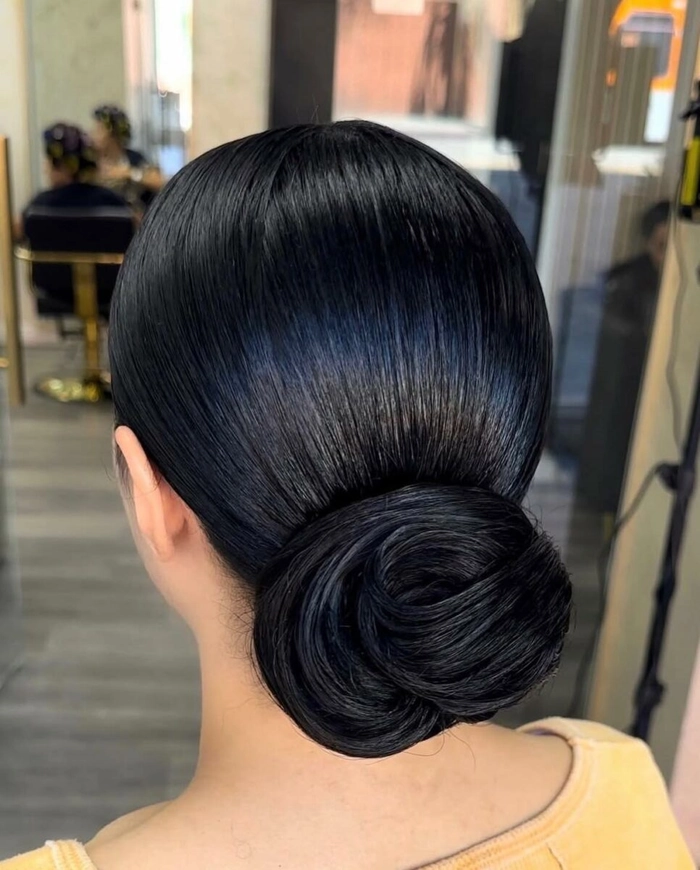 Curly hair styled in a simple slicked back bun for a casual look