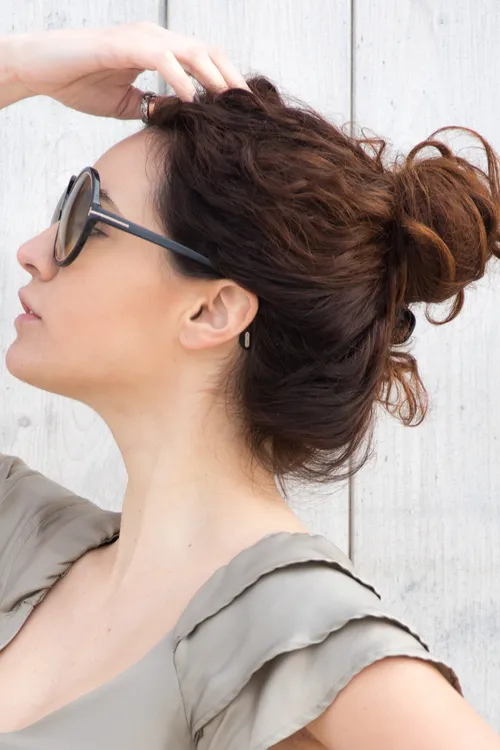 Quick High Bun Variations for Casual Athletic Wear Quick high bun variation for a casual athletic look with loose tendrils