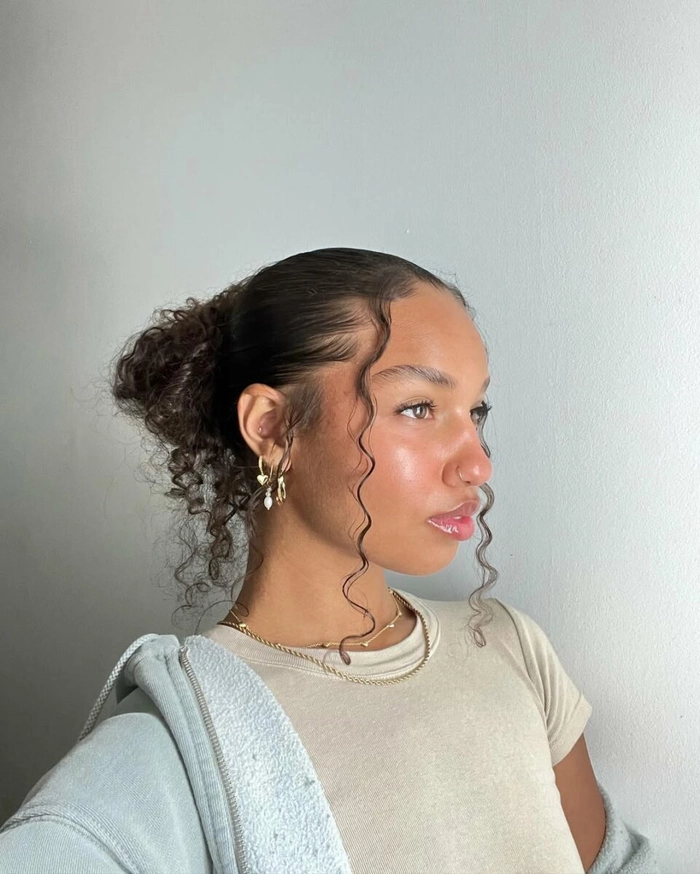 A woman with curly hair styled in a simple, sleek bun.