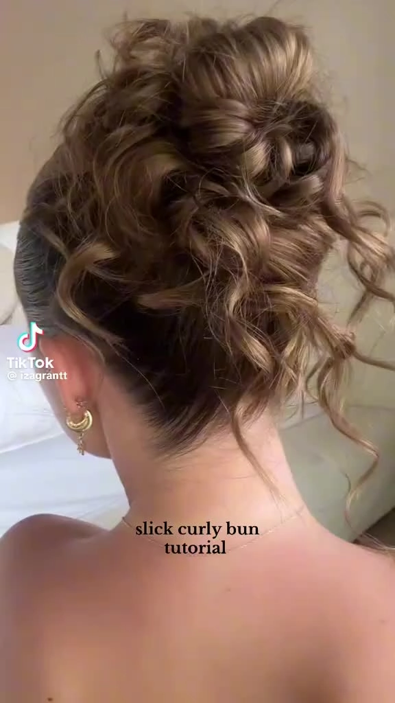 A woman with curly hair styled in a slicked back bun, showing a casual yet polished look