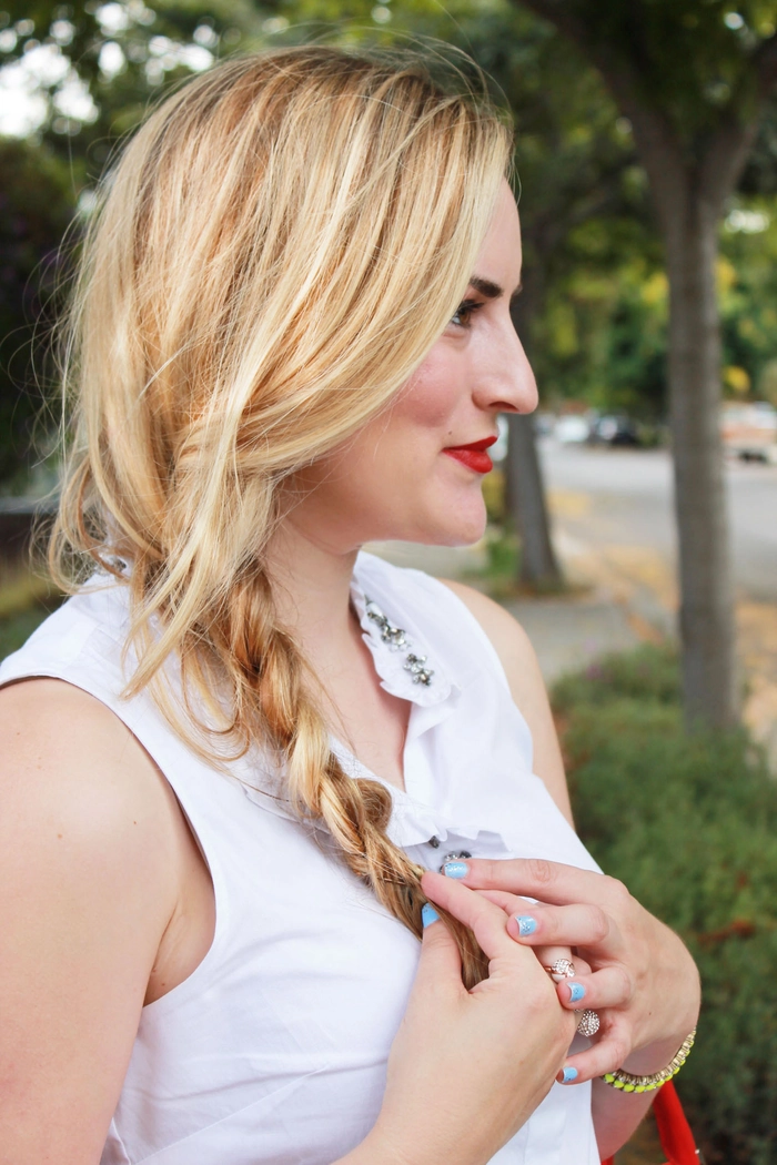 A woman with an effortless loose side braid enjoying a casual autumn walk surrounded by falling leaves