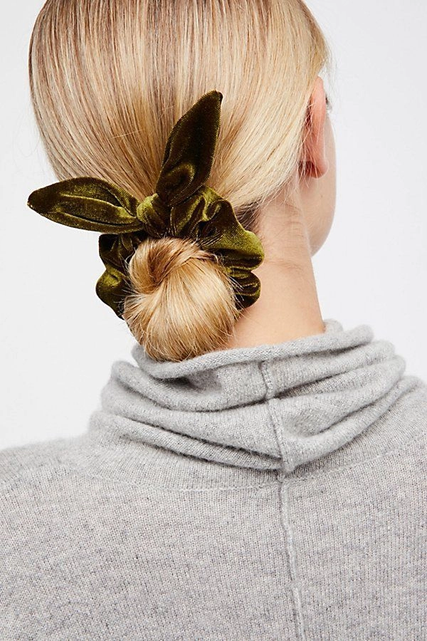 Woman with a cozy messy bun secured by a soft velvet scrunchie, wearing a chunky knit sweater